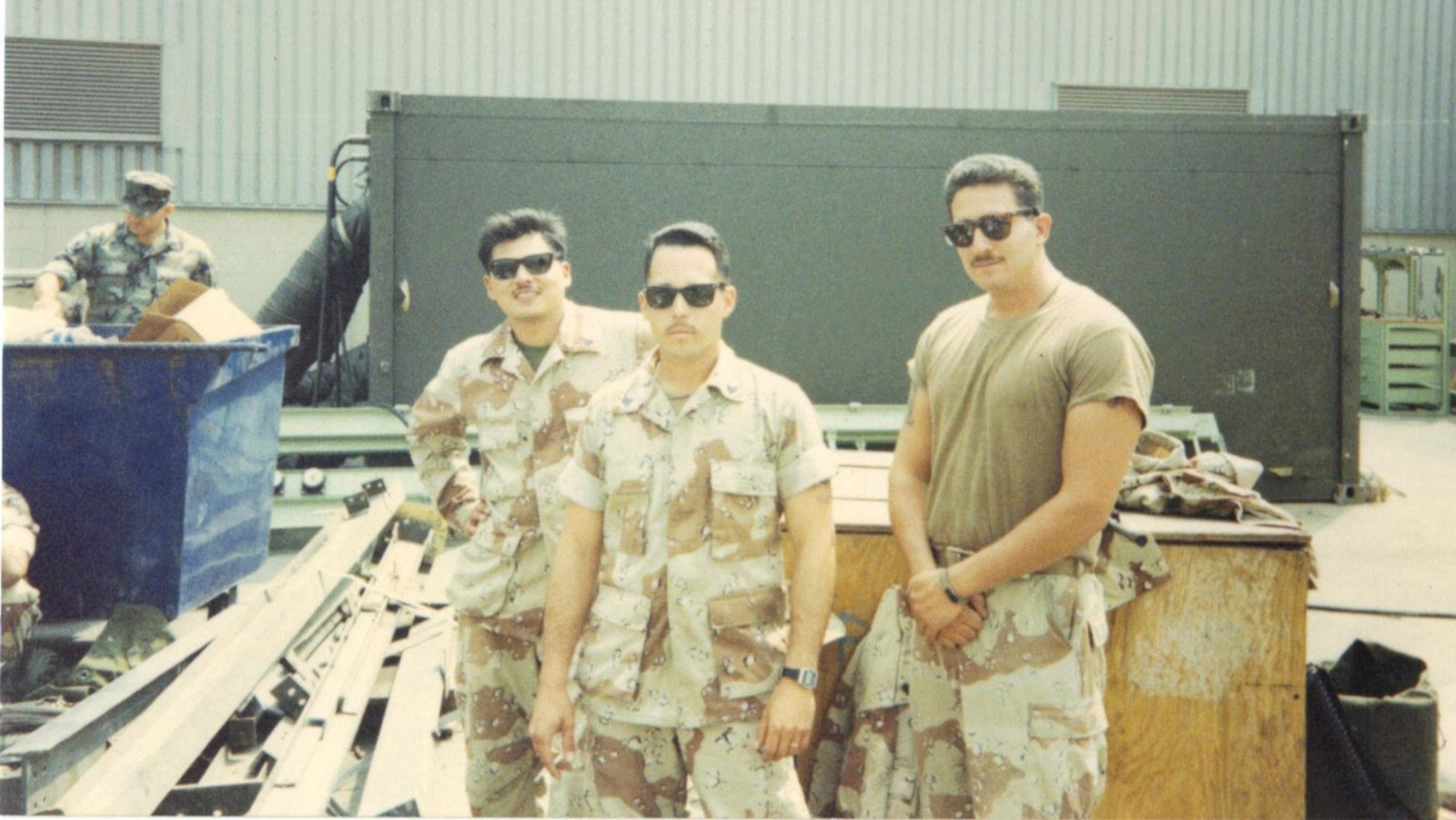 Mario Sanchez and two other members of the Marine Corps pose in front of military equipment.
