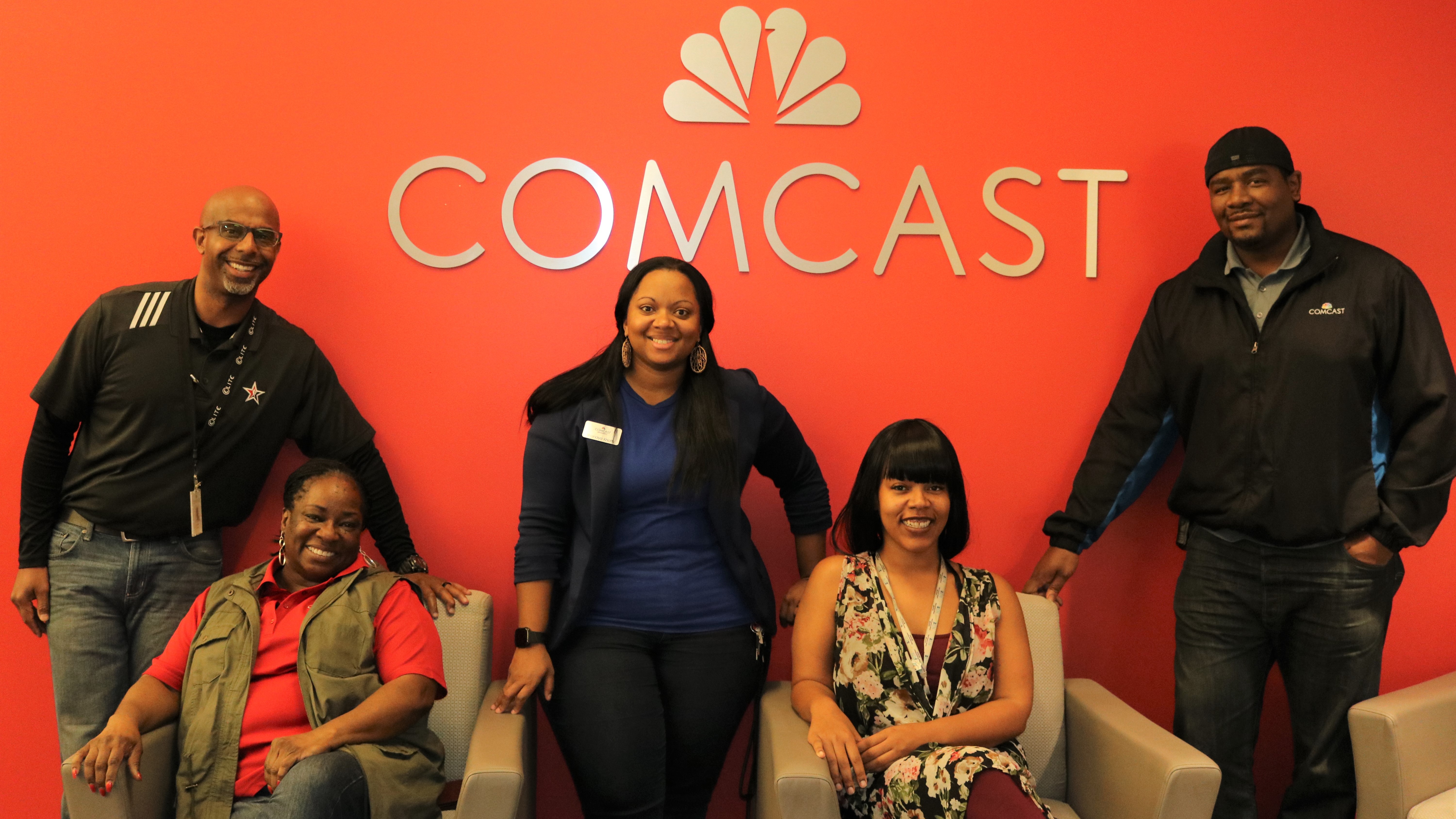 Members of Comcast’s Black Employee Network stand in front of a Comcast logo.
