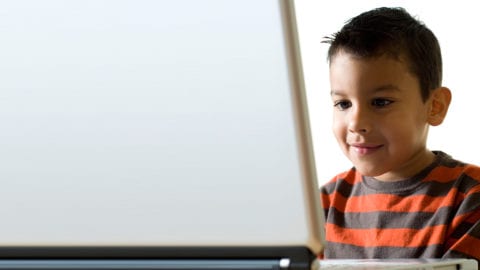 A young child uses a laptop to do homework