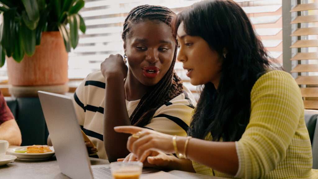 Two young women connected to fast and reliable internet at a restaurant thanks to the Xfinity network, courtesy of Comcast.