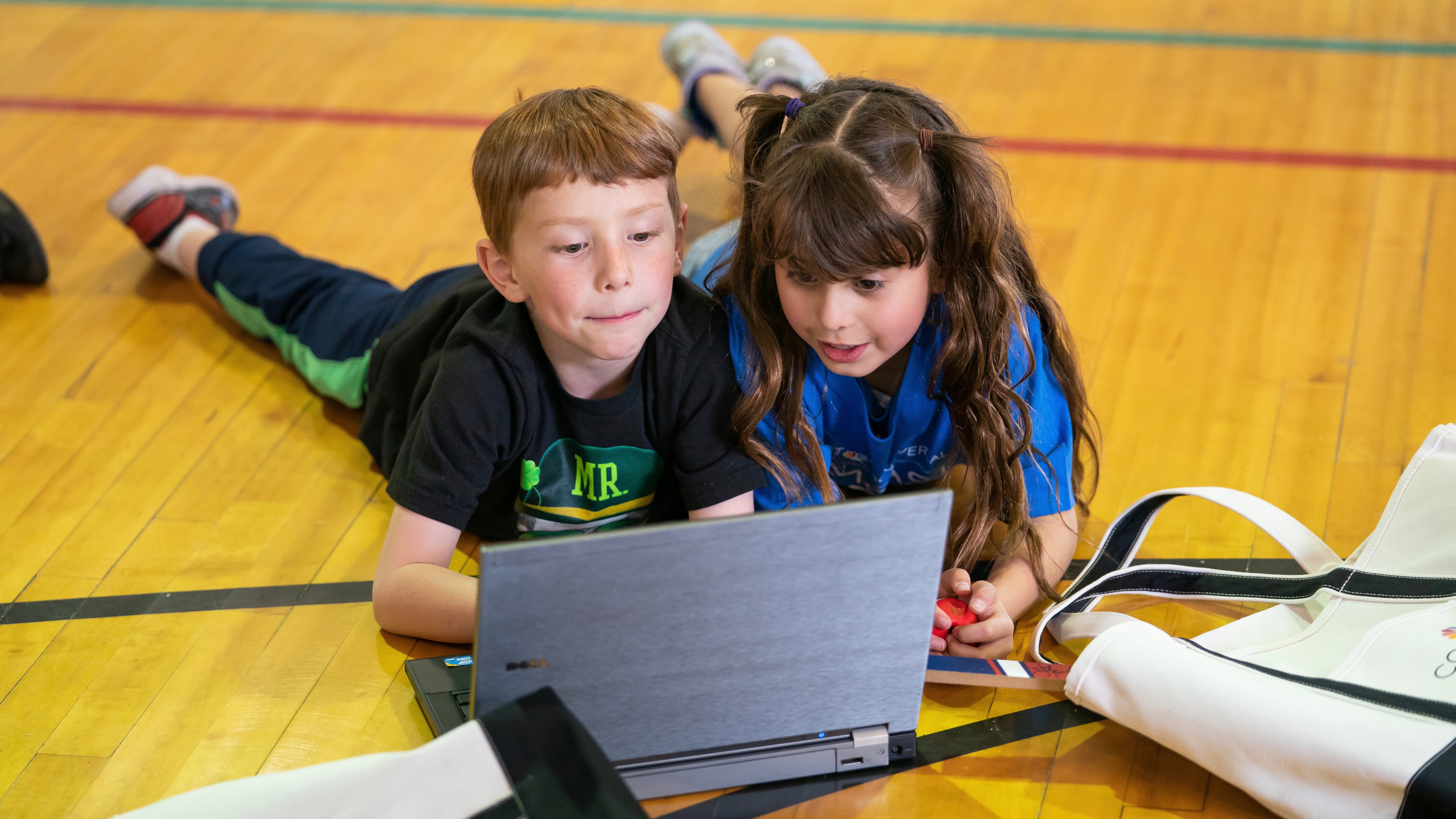 Children from the Tutt Boys & Girls Club of the Pikes Peak Region lay on the floor and use a laptop together.
