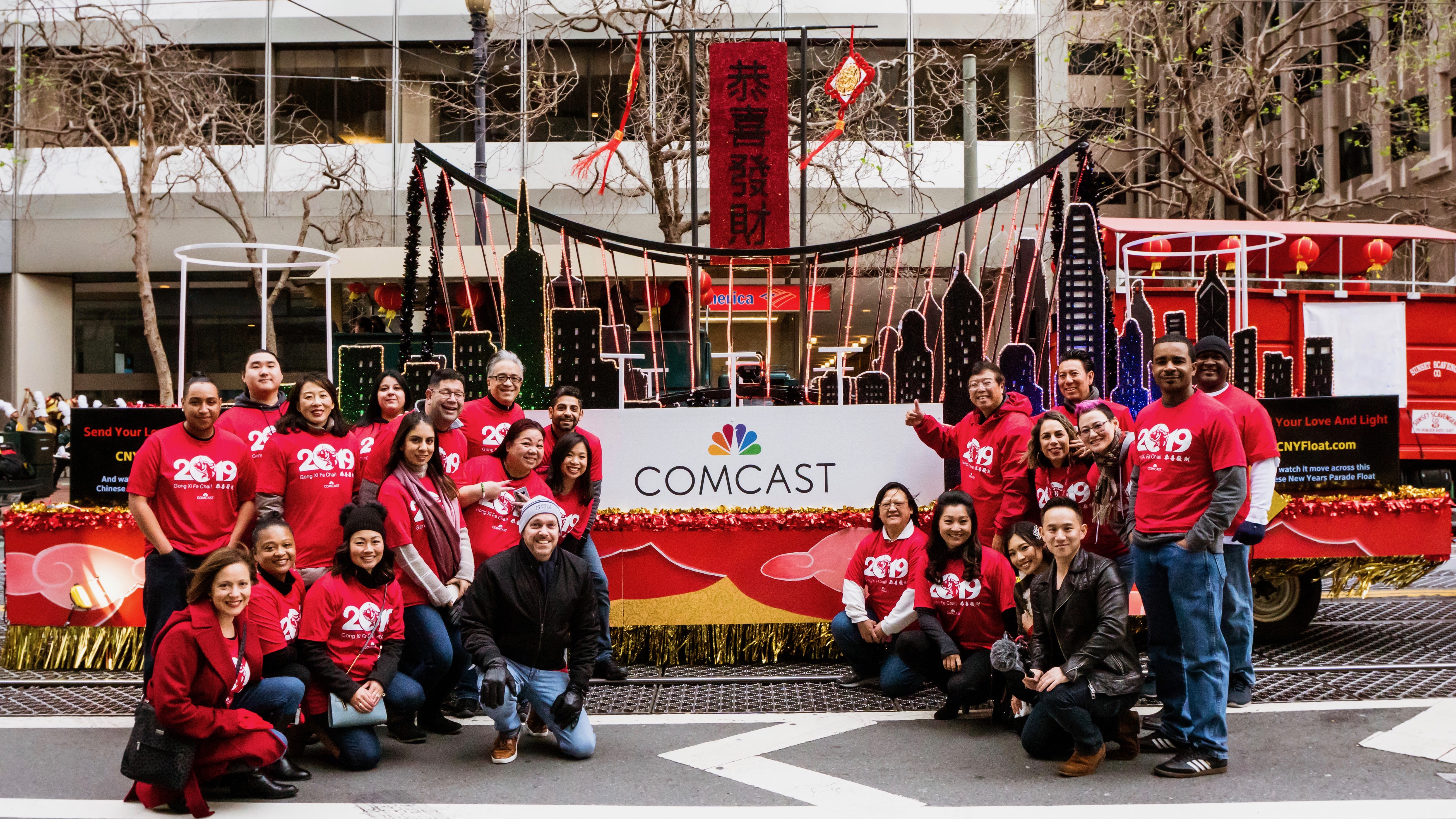 group of people posing outside of comcast