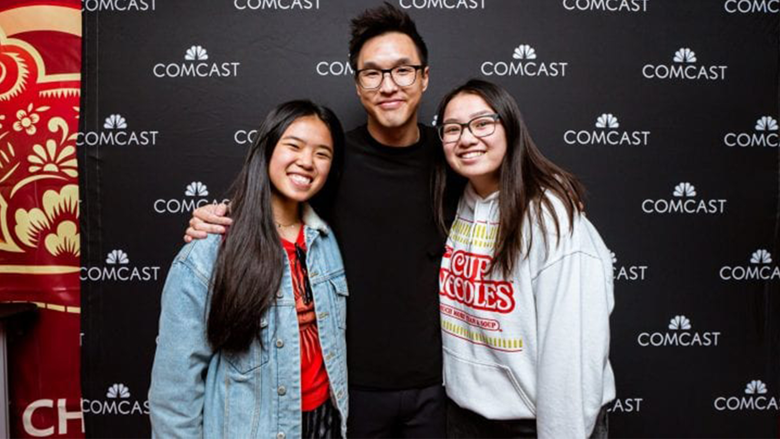 Wesley Chan in front of a Comcast branded backdrop with fans.