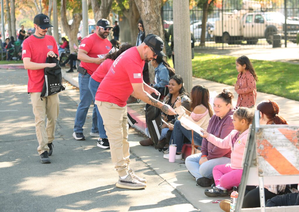 Comcast teammate hands a gift to a child at the Central Valley Veterans Day Parade 2023.