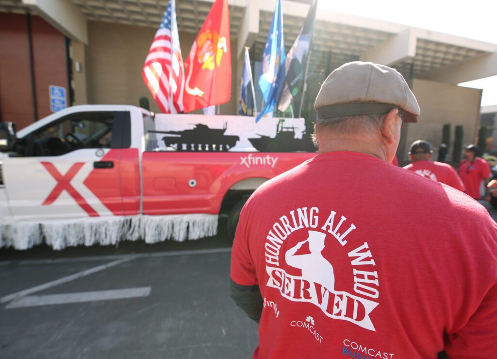 A Comcast teammate wears a red shirt that reads, "Honoring all who served," at the Central Valley Veterans Day Parade 2023.