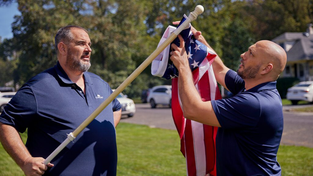 Two Comcast team members preparing an American flag to be hung.