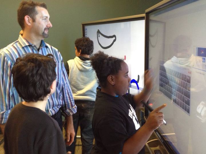 girl uses a touchscreen to operate a giant smart panel computer