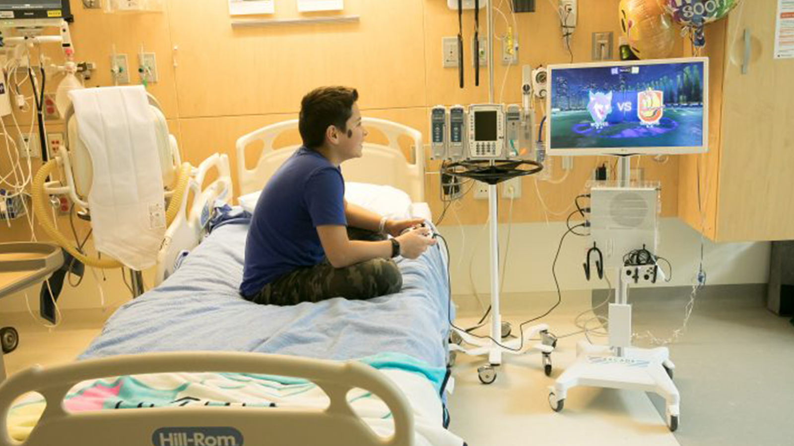 A young child in a hospital setting playing video games.