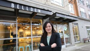 A woman dressed in a suit stands in front of Bellden Cafe.