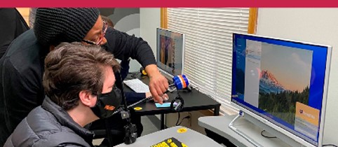 An instructor guides a student on a computer.