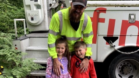 Comcast technician, Devin Fernandez smiles with his son and daughter in front of Comcast truck.
