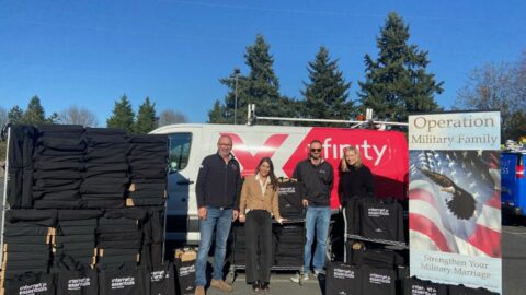 Mike Schindler of Operation Military Family stands with an Xfinity van, laptops, and Comcast staff members.