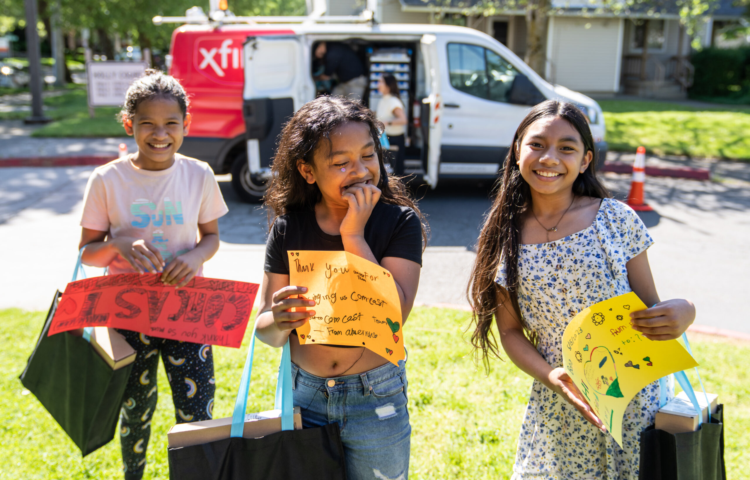 Children with laptop bags in front of an Xfinity van.