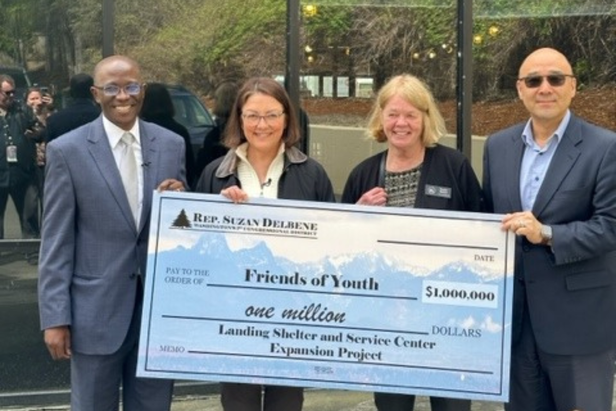 Friends of Youth staff hold a large check. 