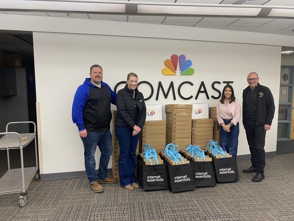 Comcast employees pose with laptops and Operation Military Family's Mike Schindler.