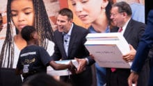 David L. Cohen and Jeremy Ford distribute free Dell laptops to children.