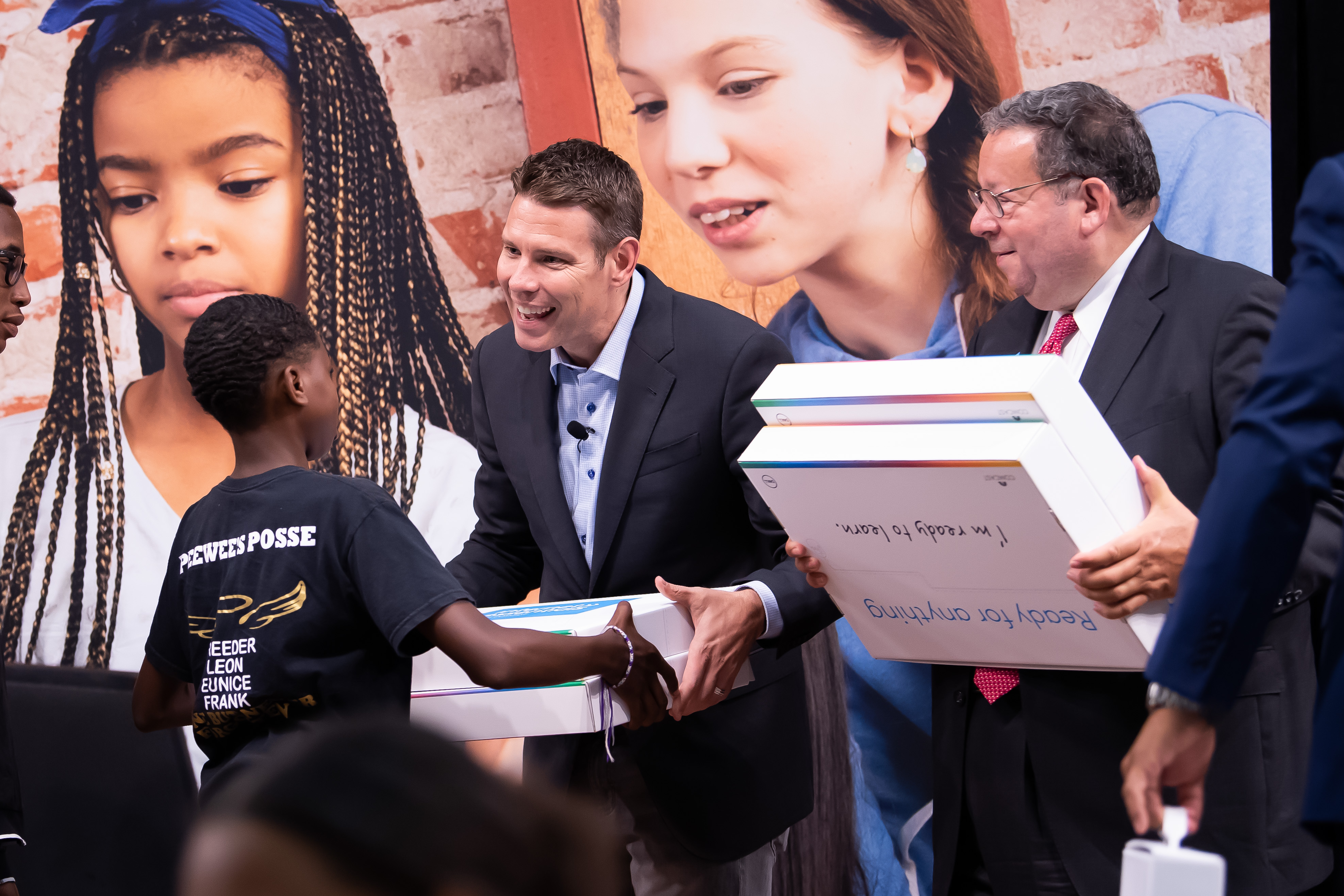 David L. Cohen and Jeremy Ford distribute free Dell laptops to children.
