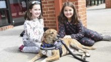 Two children sit with a service dog