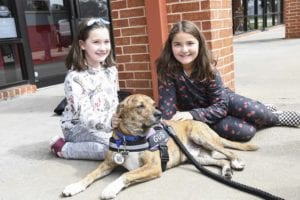 Two children sit with a service dog