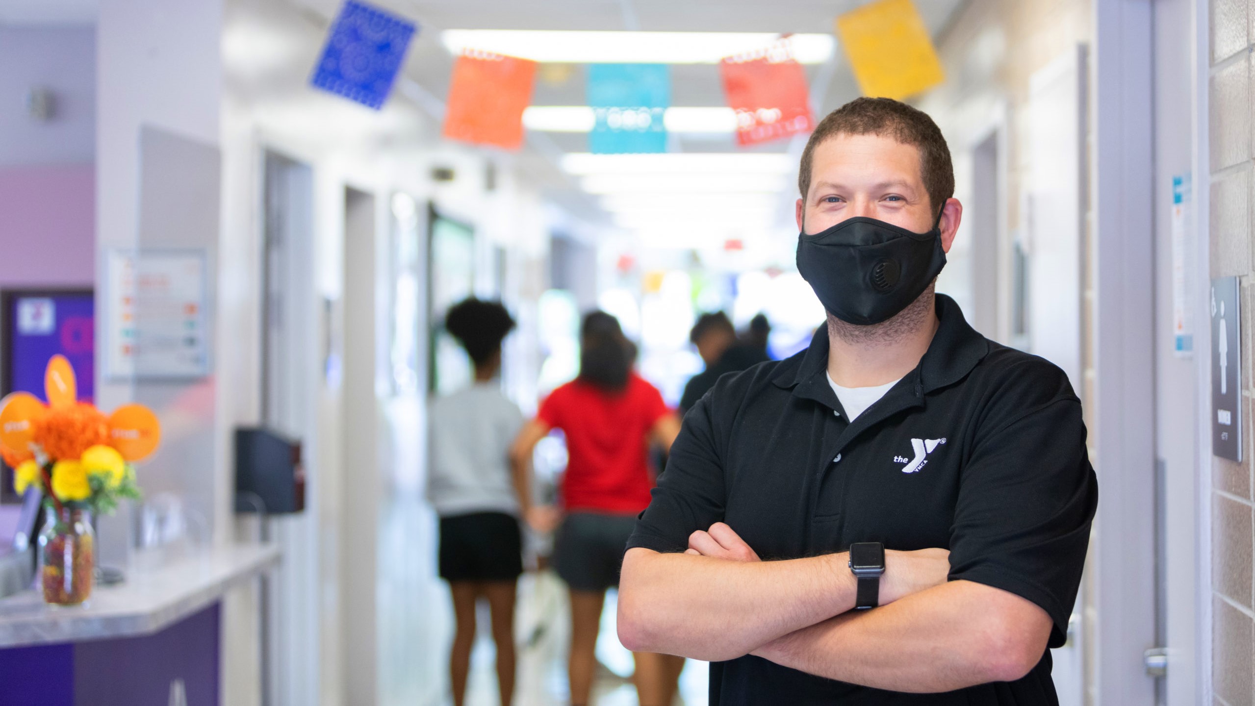 A masked YMCA instructor in a hallway