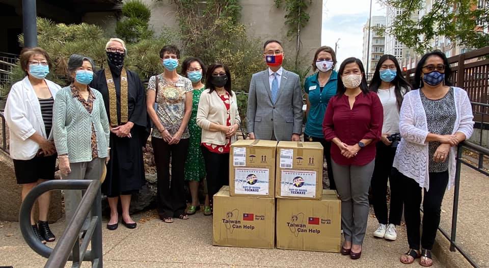 A group of masked people stand behind several boxes of Taiwanese goods.