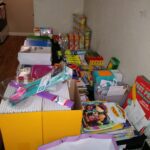 Many boxes and bags of school supplies lining a wall in a room