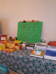 A table with patterned tablecloth holding various school supplies