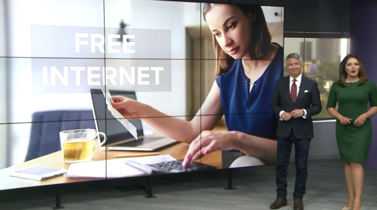 Two news presenters standing in front of screen displaying the text "Free Internet".