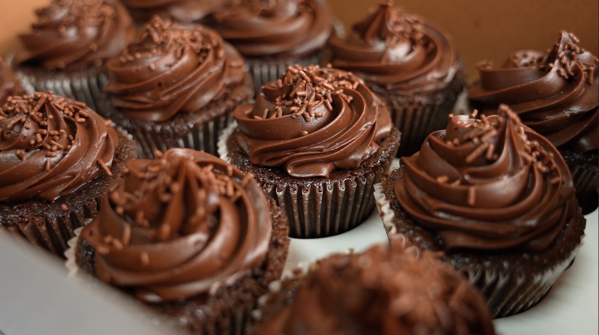 A dozen chocolate frosted cupcakes