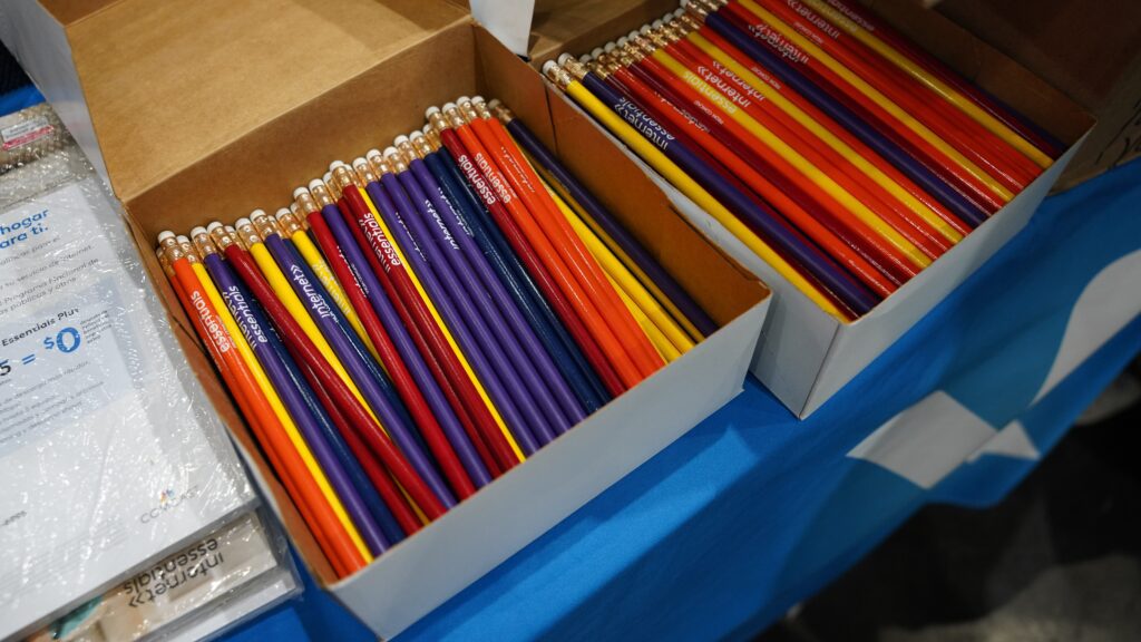 Two boxes open on table containing many pencils printed with Internet Essentials logo