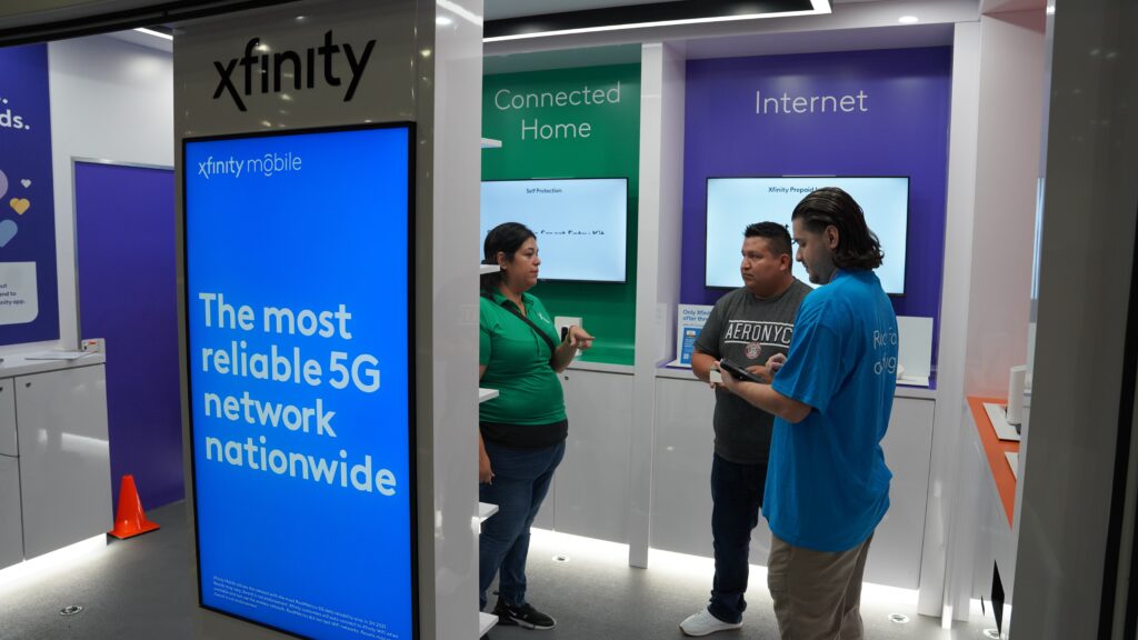 Three people standing near multiple Xfinity services signs