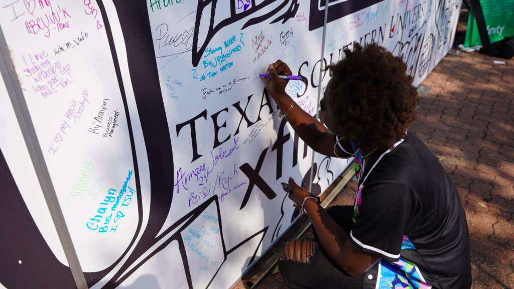 Student signing the TSU Xfinity wall