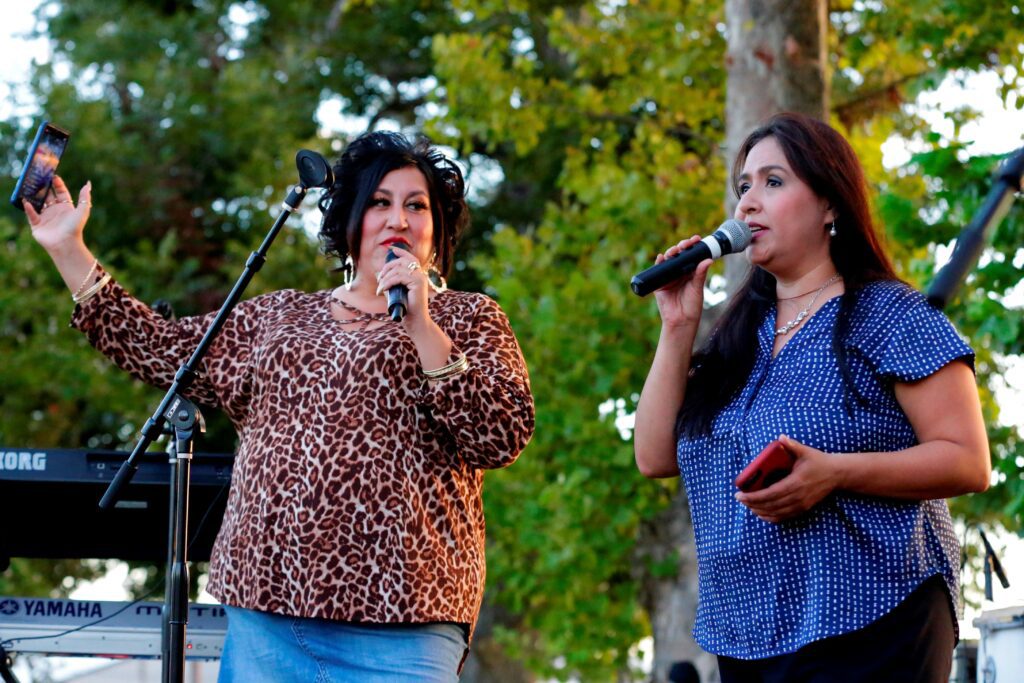 Two women holding microphones and cell phones