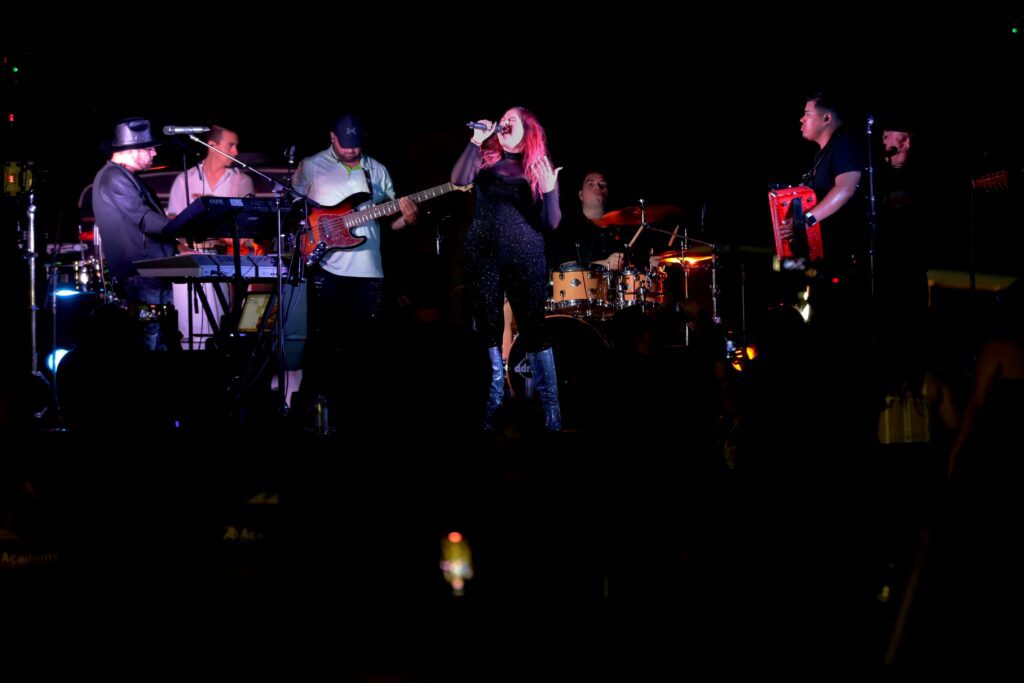 A woman singing with band behind her