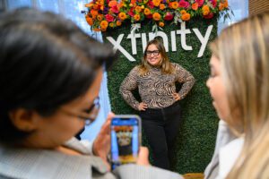 Woman with hands on hips posing for picot in front of a floral decorated Xfinity wall