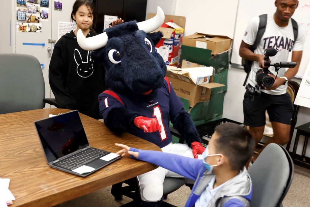 Mascot sitting with young boy seated in front of laptop
