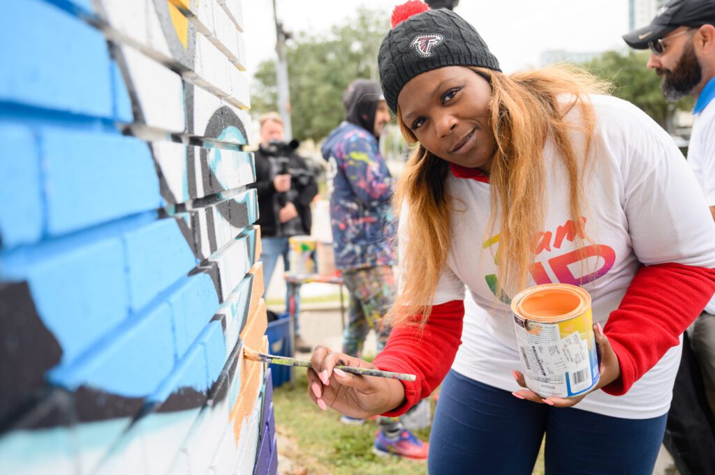 Comcast Texas volunteer with Team UP helps paint the mural.