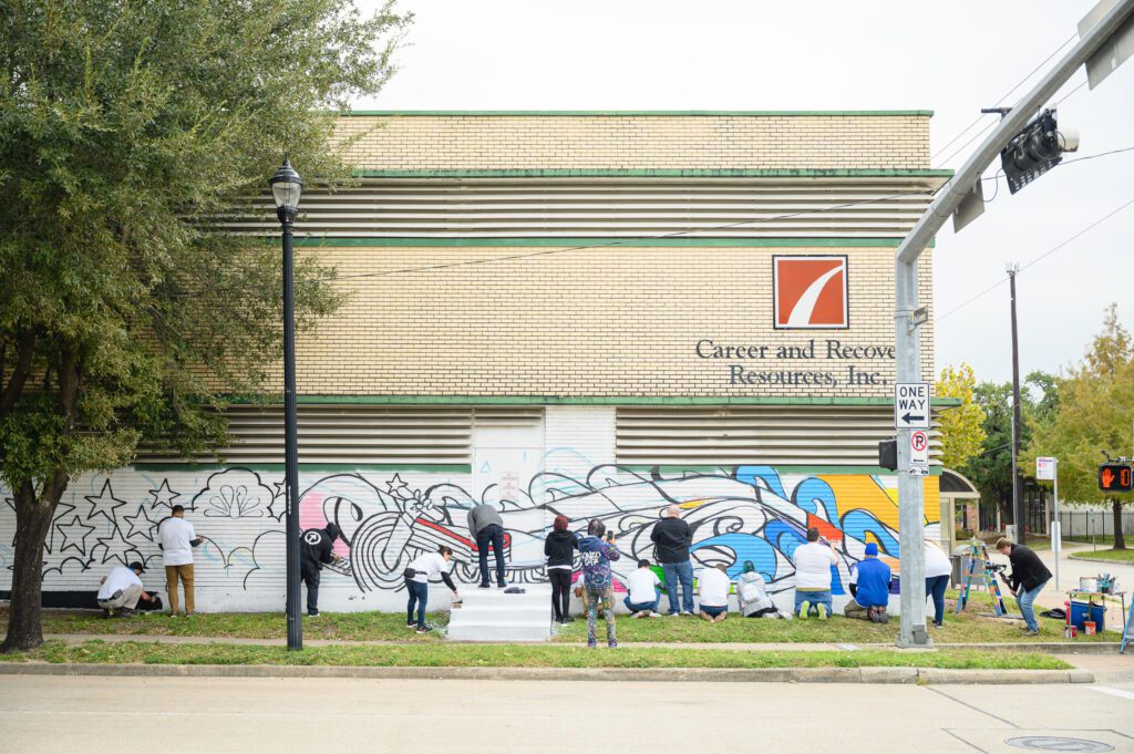 Image from a distance of group of volunteers painting mural