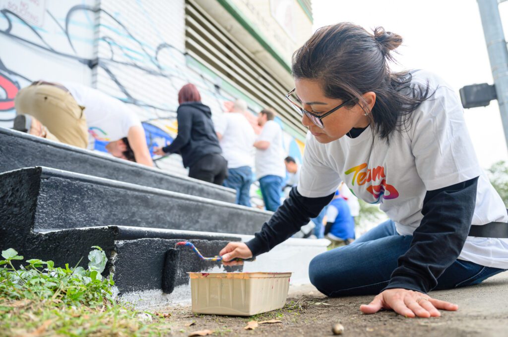 A female volunteer sitting on the ground while painting steps black