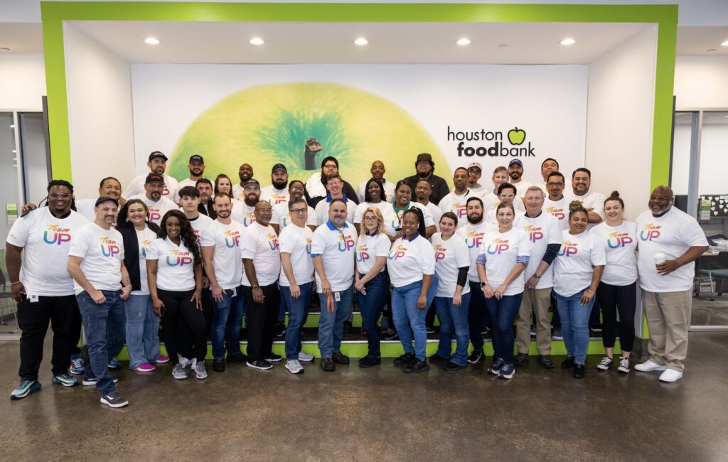 Large group of Team Up volunteers posing for picture at Houston food bank.