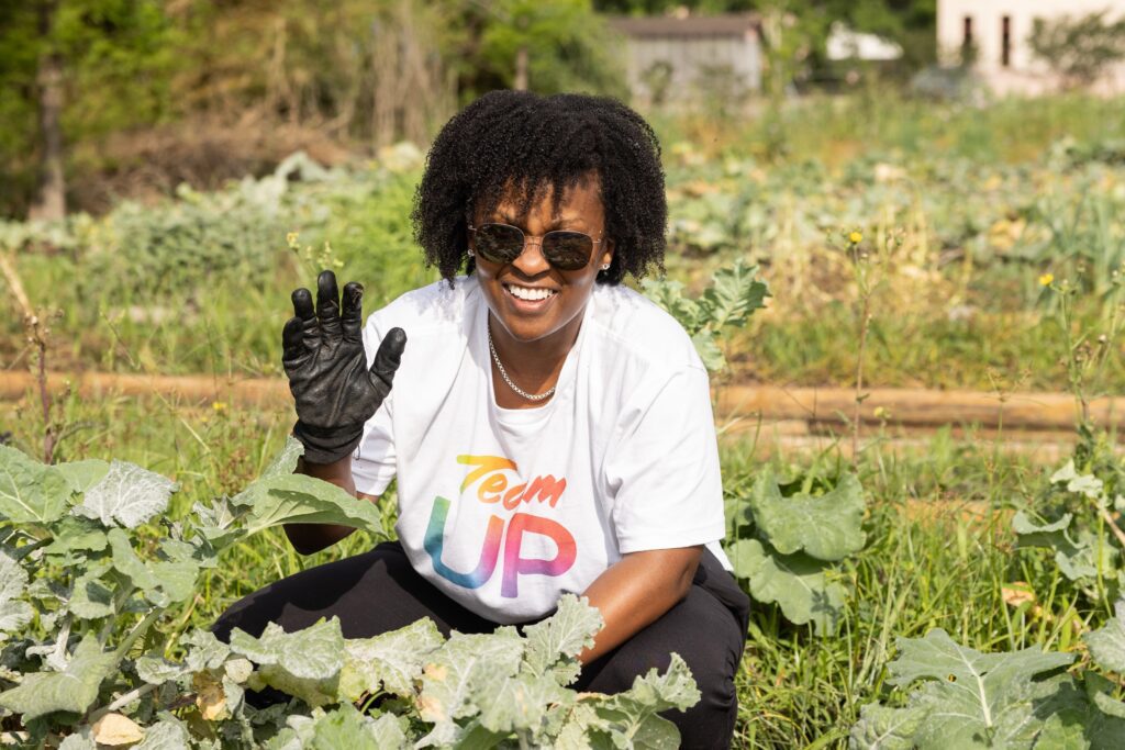 Volunteer smiling and waving gloved hand in garden