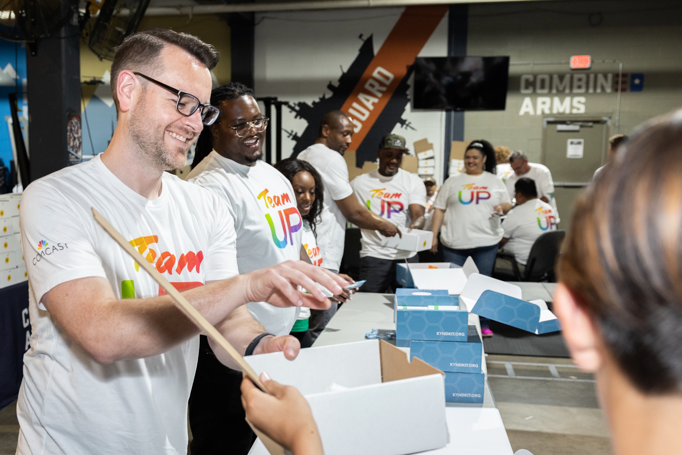 A Comcast volunteers helps to box a hygiene kit for a veteran at Combined Arms in Houston, Texas.