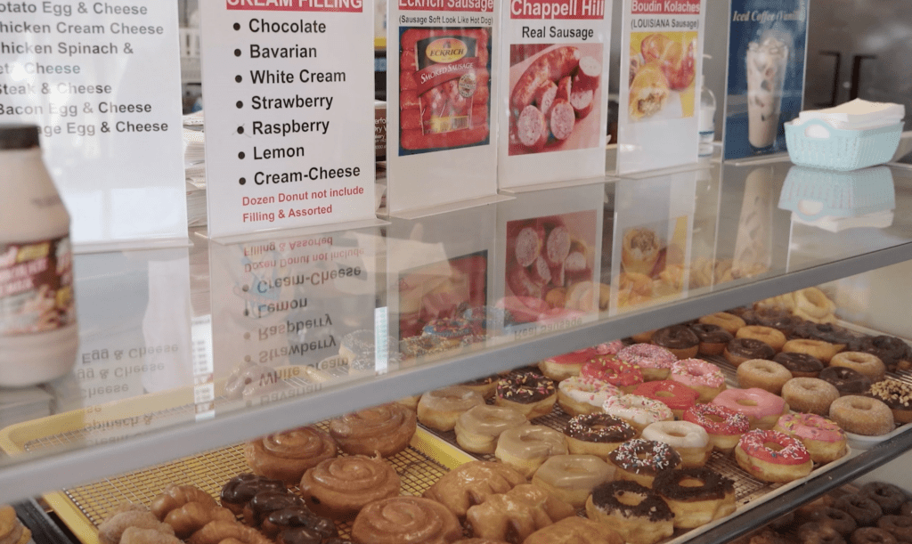 Glass display case featuring many different varieties of doughnuts