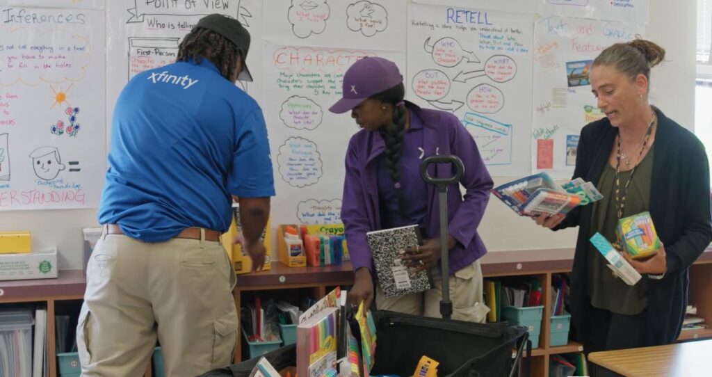 Technicians help Coovert unpack school supplies
