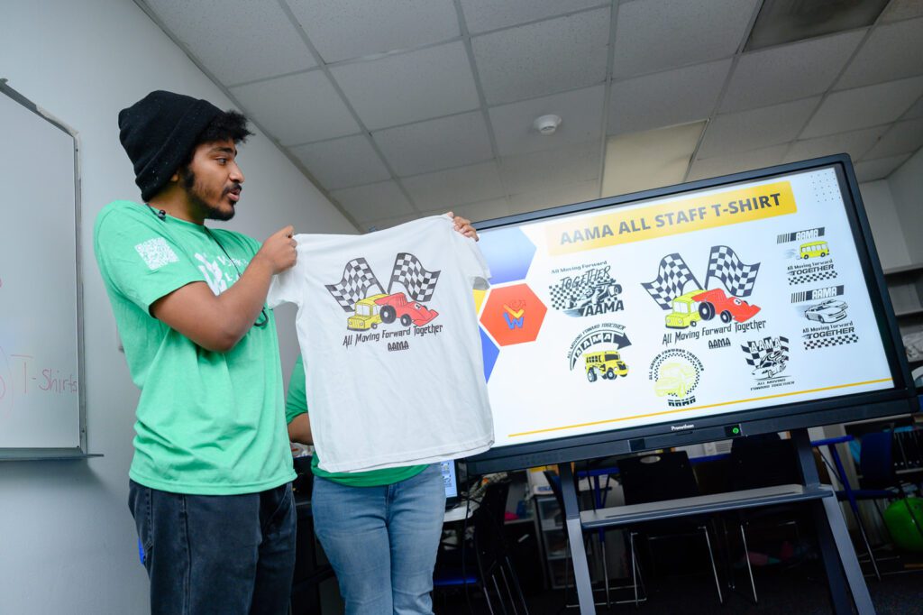 A student holds up a T-shirt he designed.