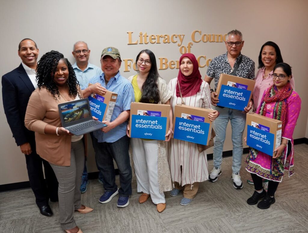 Members of the Literacy Council of Fort Bend County hold laptops from Comcast.