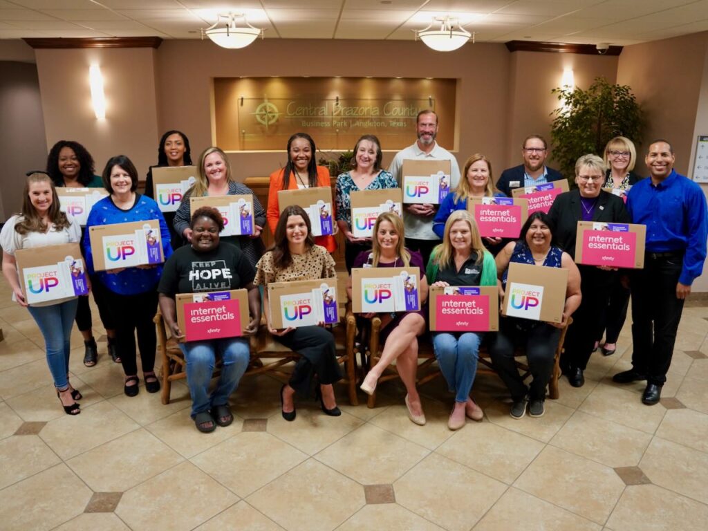 Several non-profit partners smile with computers for a group photo at United Way of Brazoria County.