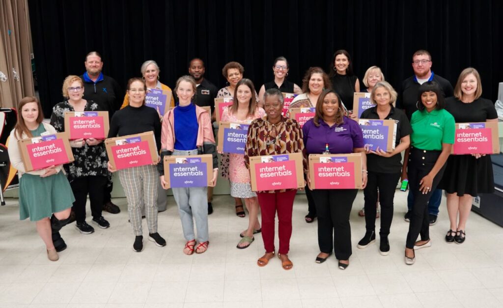 Representatives from non-profit partners gather for a group photos with their new laptops from Comcast. 