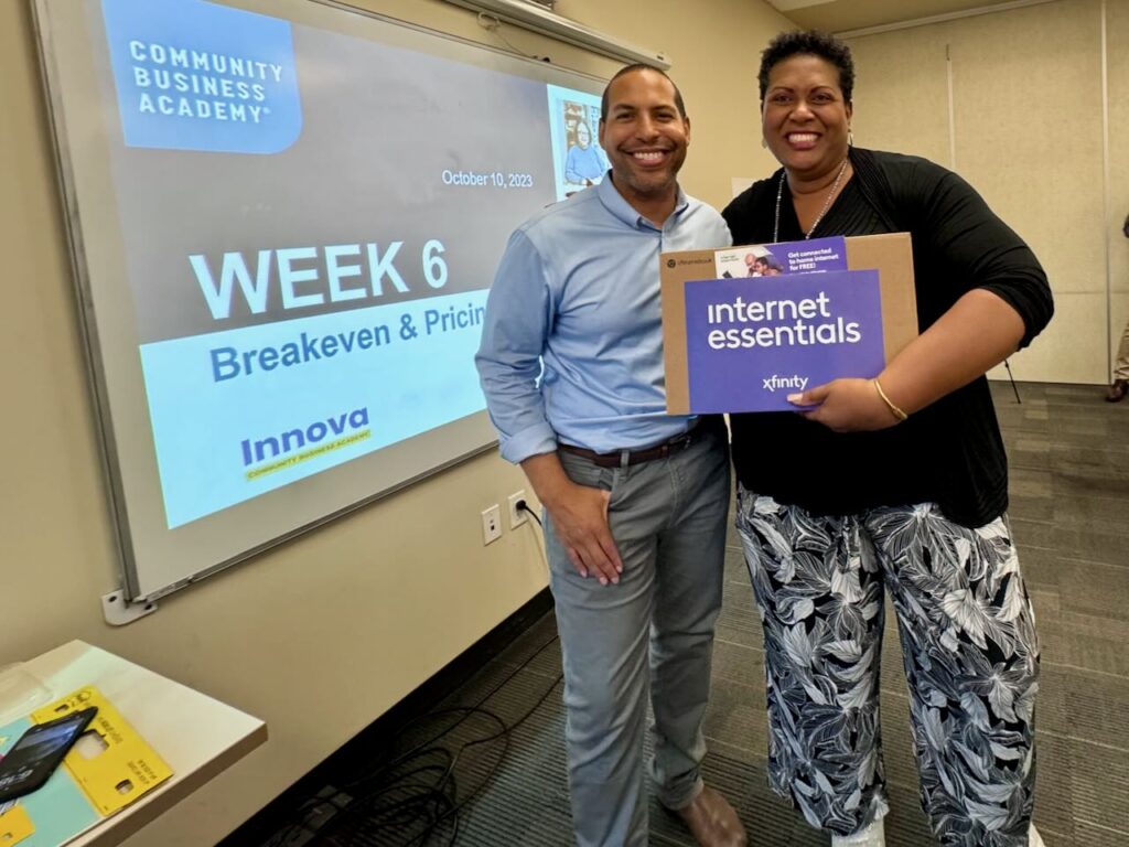 Comcast representative smiles with a nonprofit partner who received a laptop during Digital Inclusion Week.