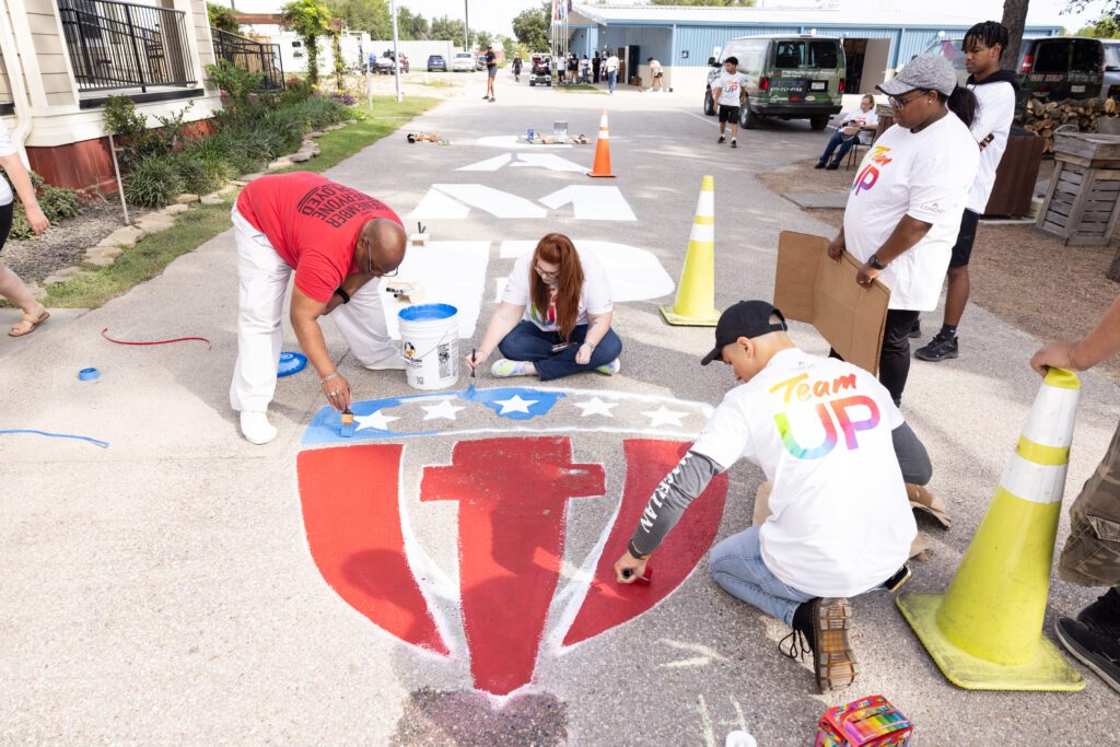 Volunteers work to paint the street at Camp Hope.